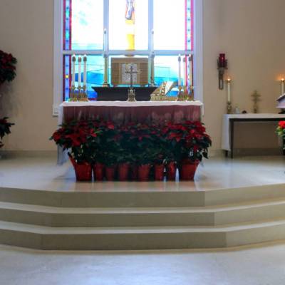 A church altar with red flower vases and red flowers