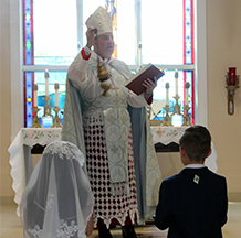 A priest conducting a first communion mass for a girl and a boy
