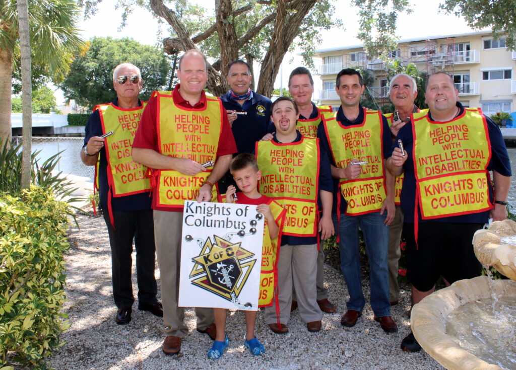 A group pf men wearing a vest with statement “helping people with intellectual disabilities”