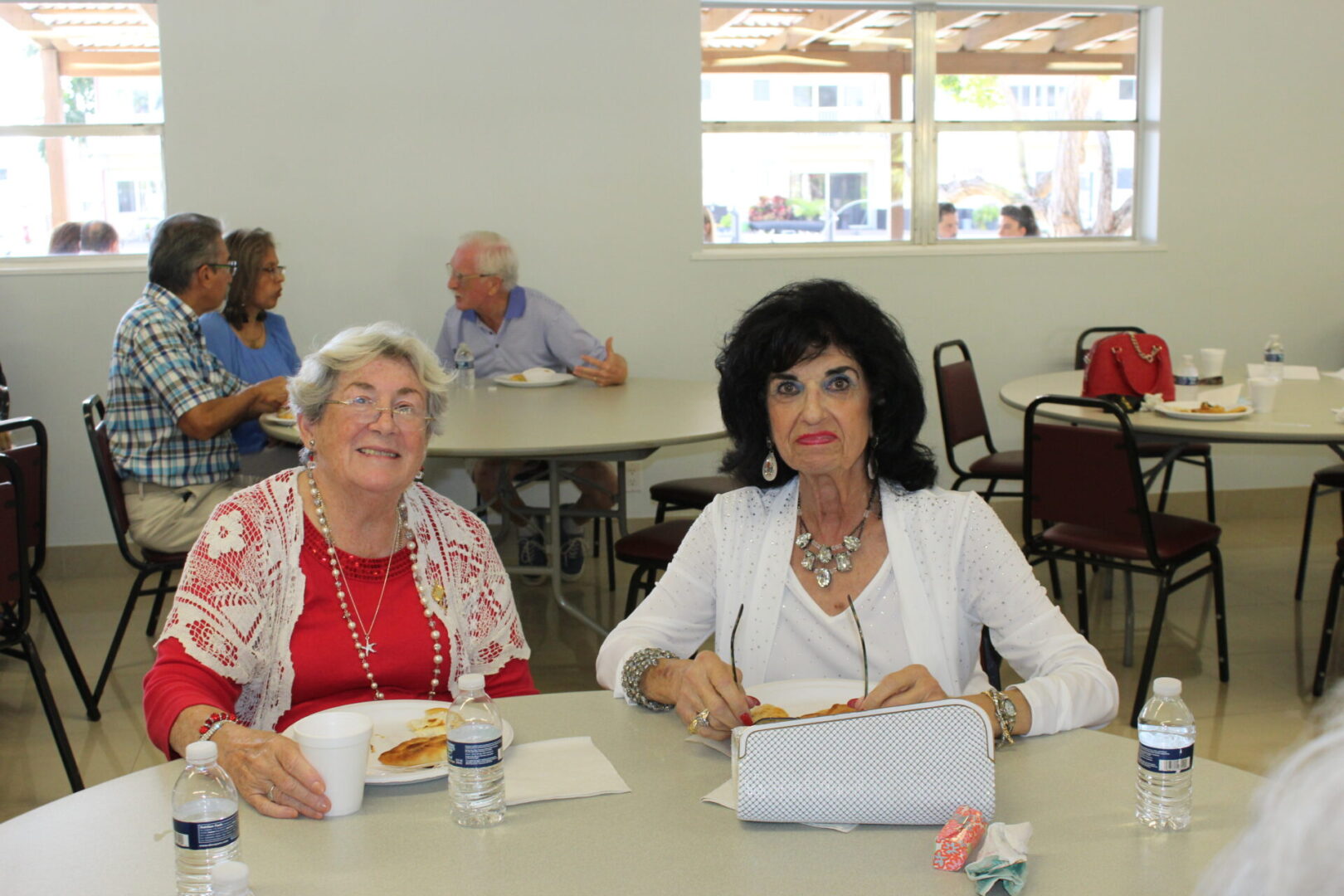 Two women eating their meal with three bottles of water