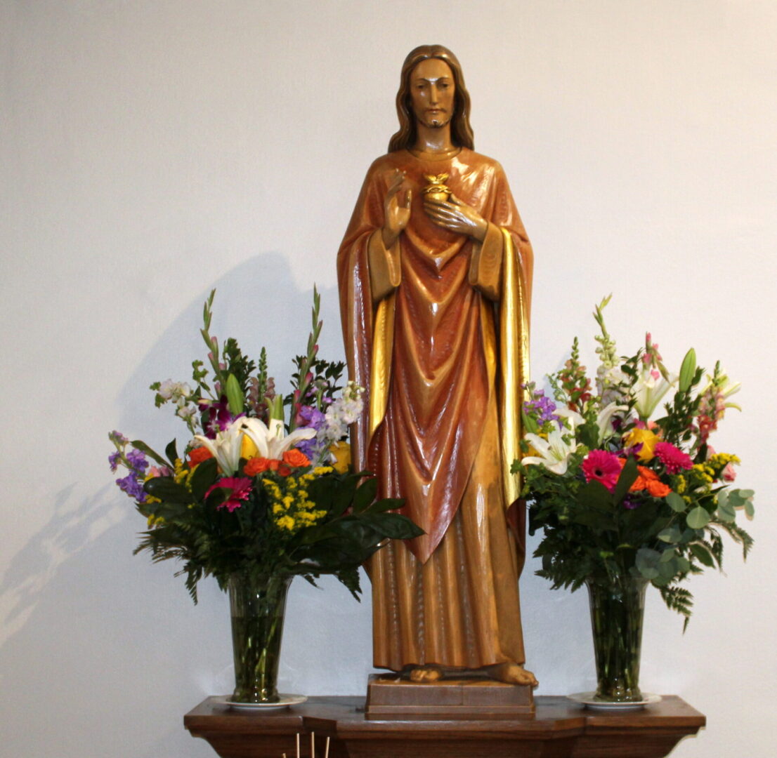 The statue of Jesus with two vases of colorful flowers