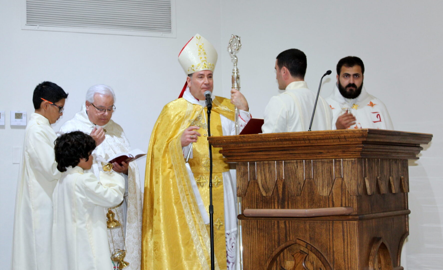 A bishop wearing a gold vest while talking in front of the church