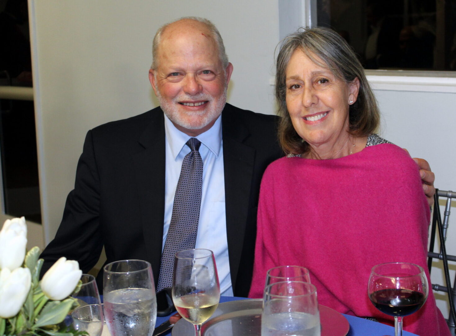 A man wearing a black suit and a woman wearing a pink cover