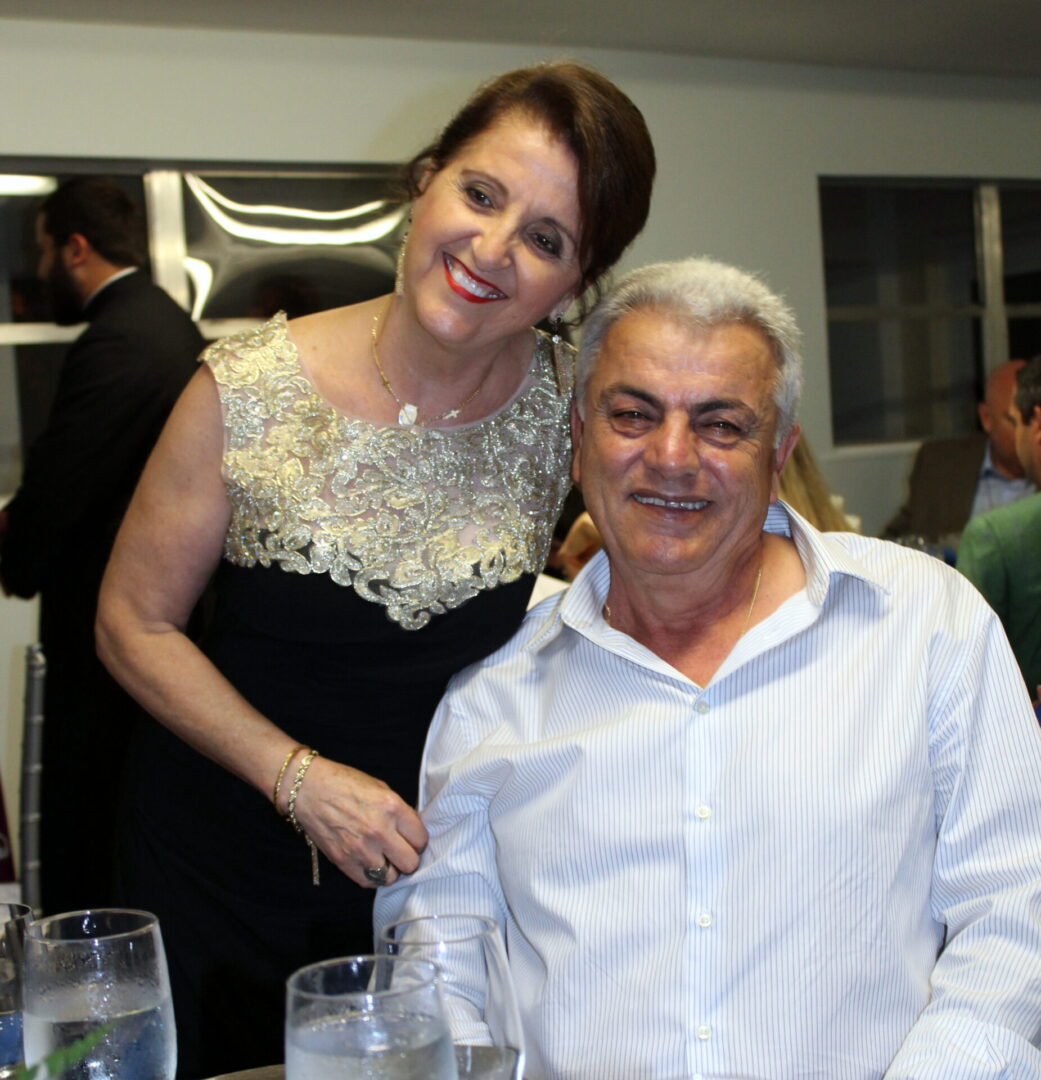 A man wearing a white polo and a woman wearing a black dress with gold details on the neck area