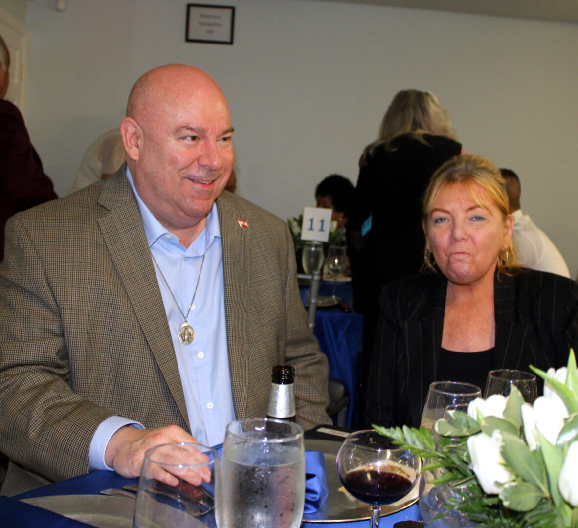 A man wearing a brown suit and blue polo and a woman wearing a black suit