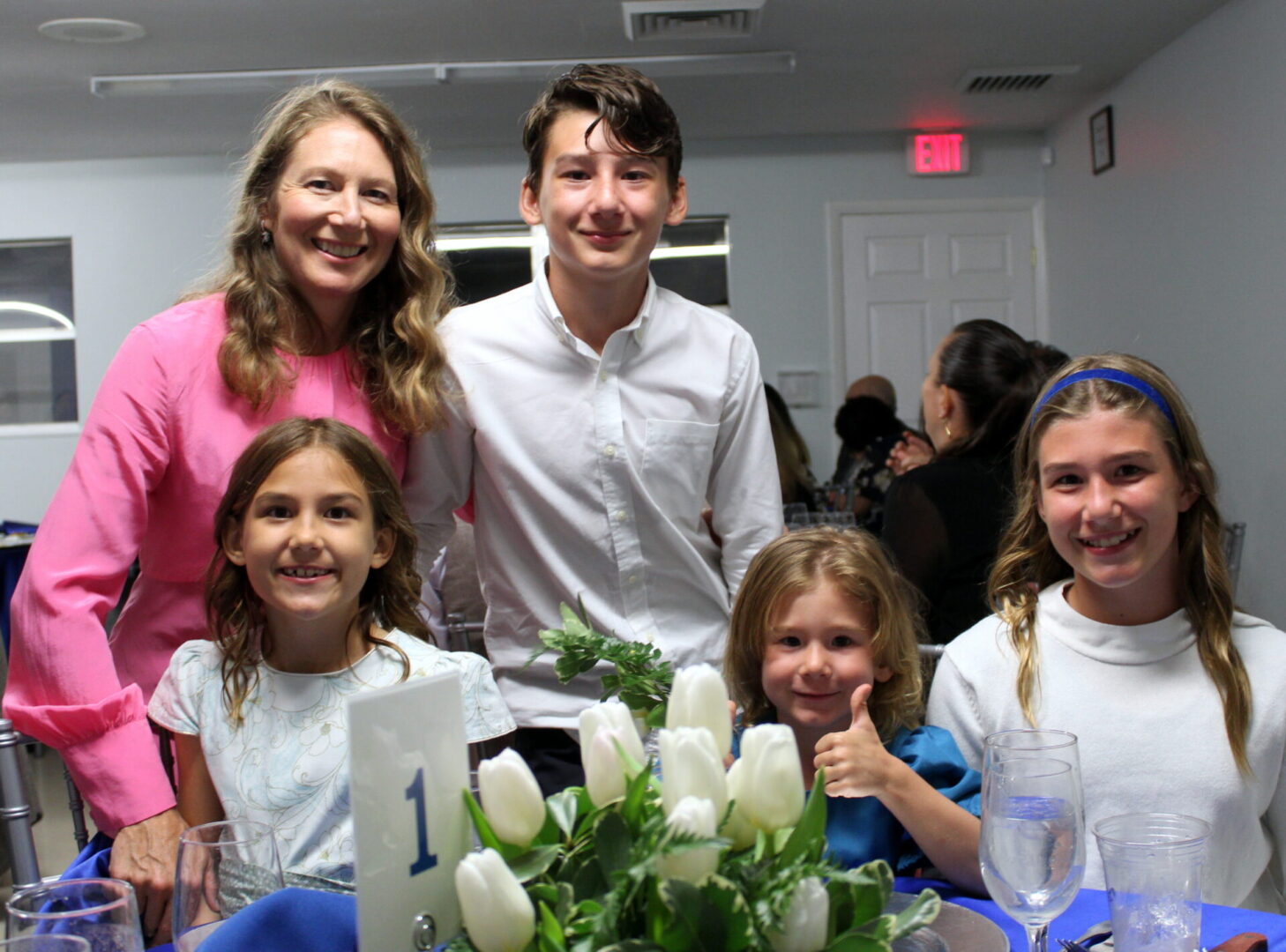 Four children and a woman wearing a pink dress on table number 1