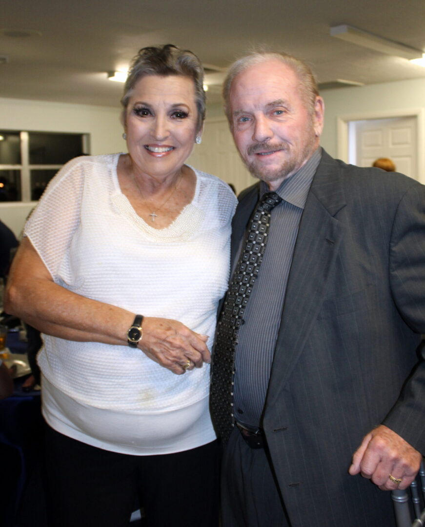 A man wearing a gray suit and a woman wearing a white top