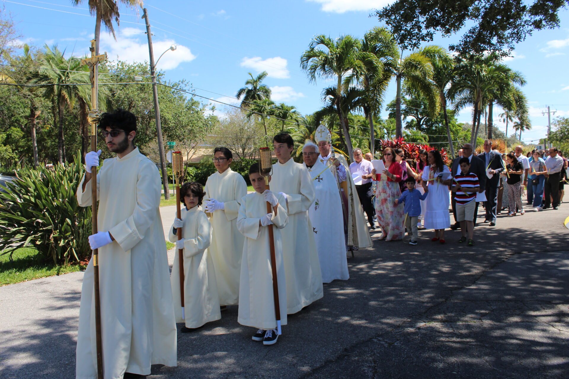 A parade with sacristans, priests, and a bishop along with the people