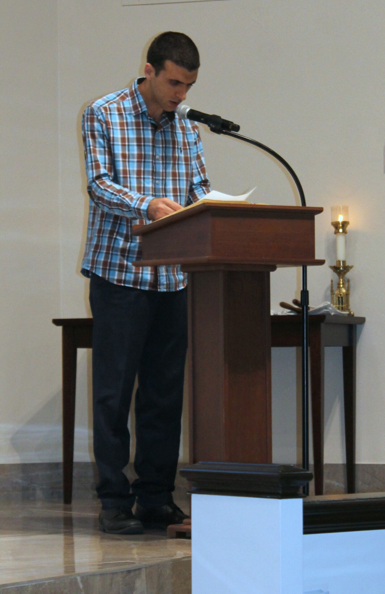 A man wearing a blue plaid top and navy-blue pants