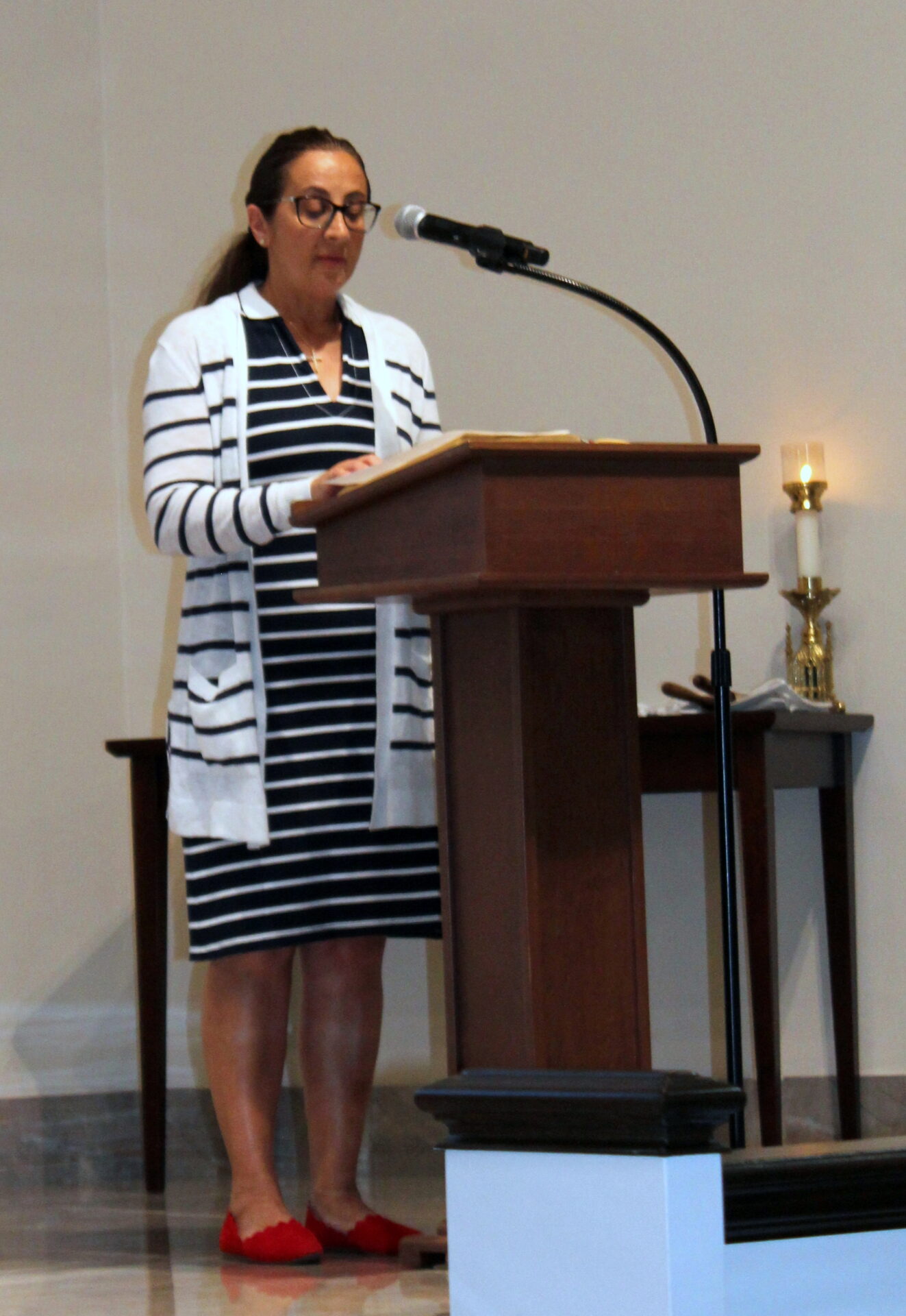 A woman wearing a dress and cardigan with black-and-white stripes design and a pair of red shoes