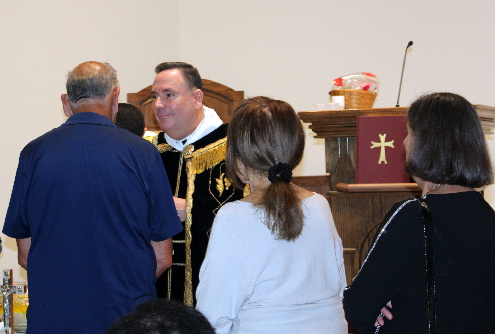 A man wearing a blue polo in front of a priest