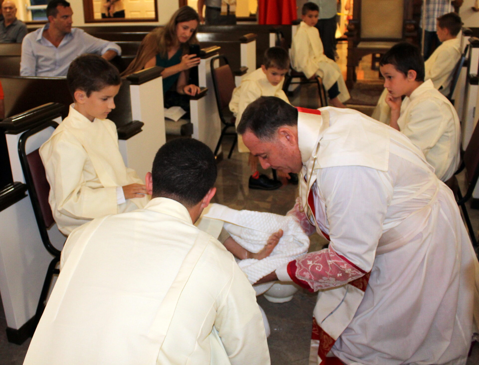 Young sacristans watching the priest washing another young sacristan’s feet