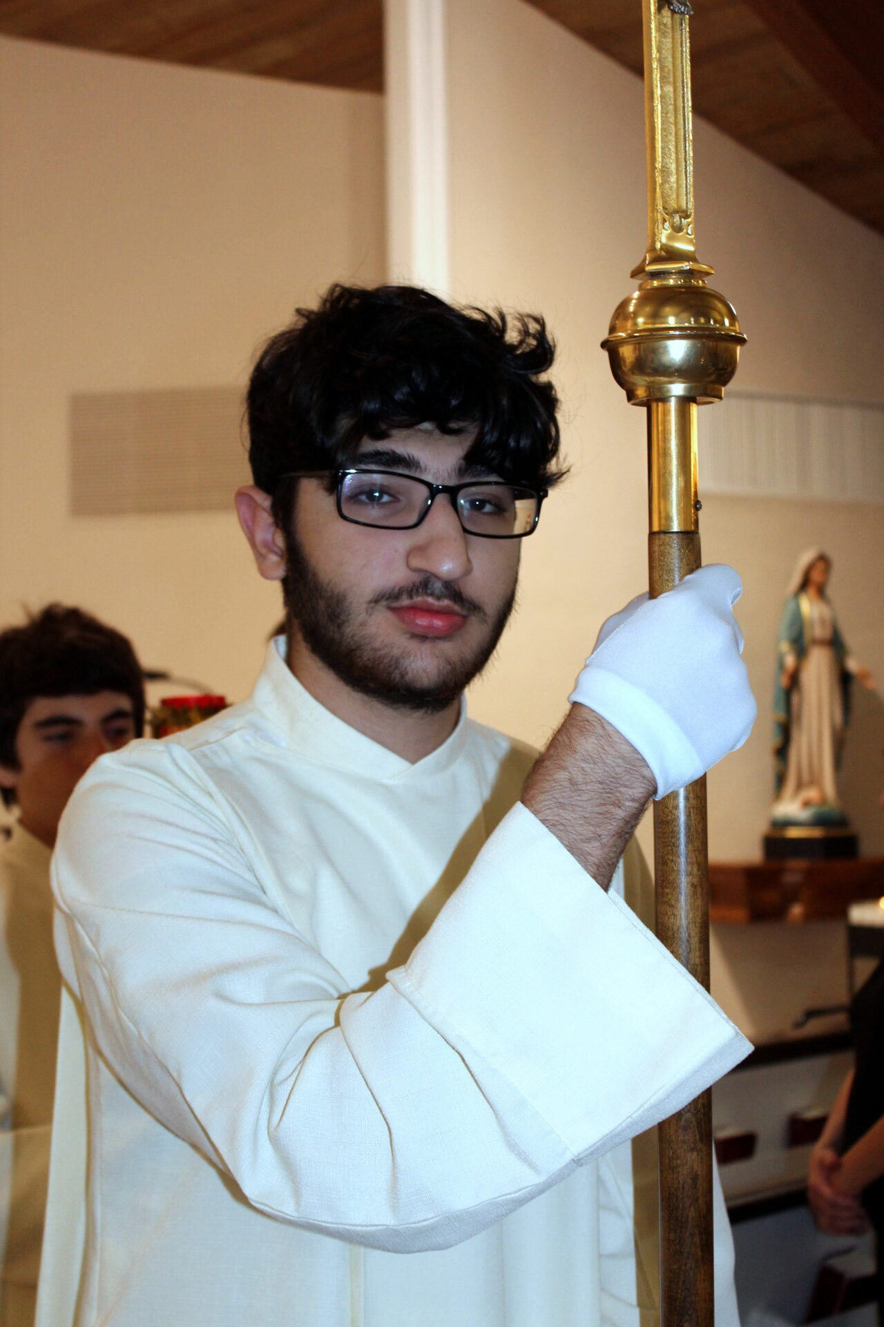 A sacristan with black eyeglass and white gloves