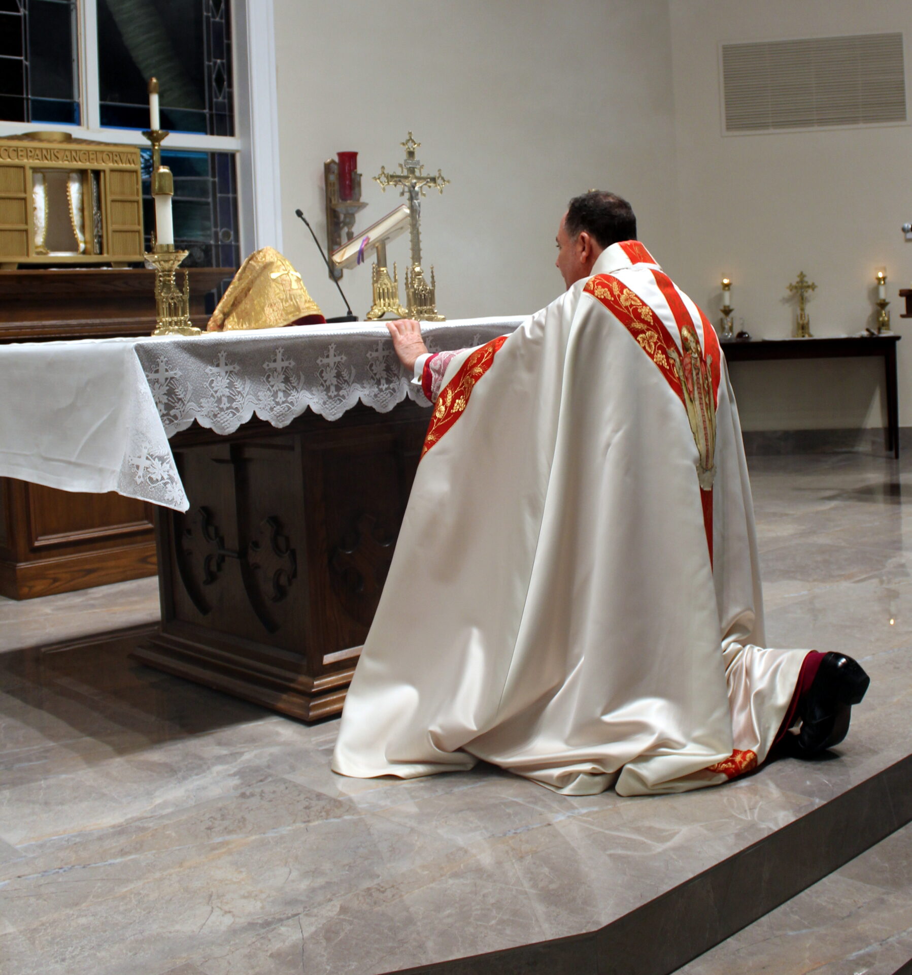 A priest kneeling down at the altar
