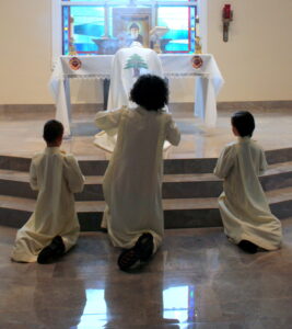 Three sacristans kneeling on the altar
